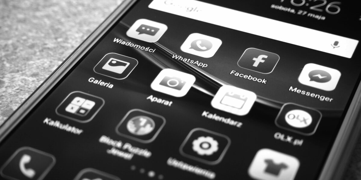 Celular em cores preto e branco com lista de aplicativos na tela. Representa atualização do WhatsApp em Setembro