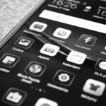Celular em cores preto e branco com lista de aplicativos na tela. Representa atualização do WhatsApp em Setembro