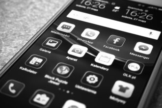 Celular em cores preto e branco com lista de aplicativos na tela. Representa atualização do WhatsApp em Setembro